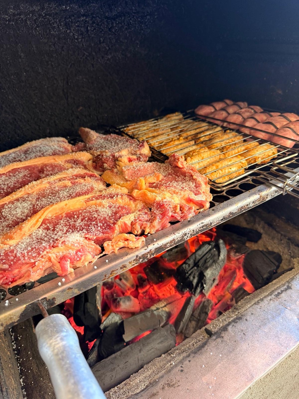 Costela e linguiça na grelha sobre carvão em brasa